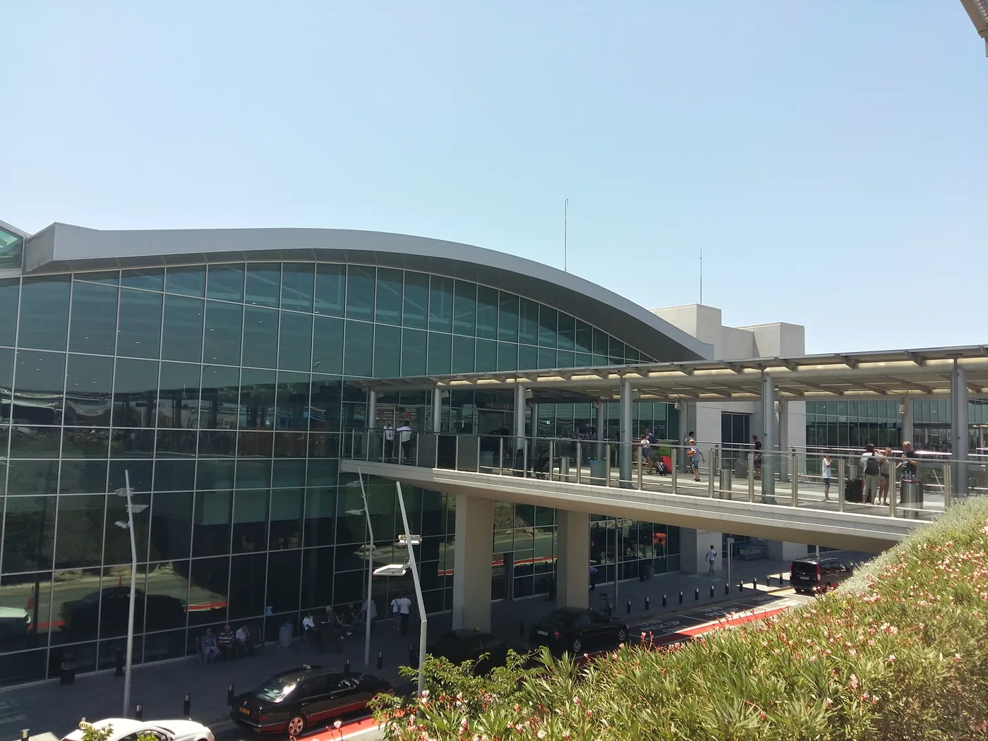 The glass-fronted terminal of Larnaca International Airport, with a covered walkway along the departures road.